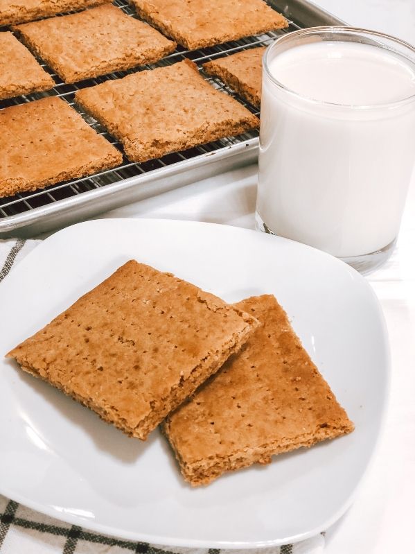 Close up of graham crackers on a white plate with a glass of milk