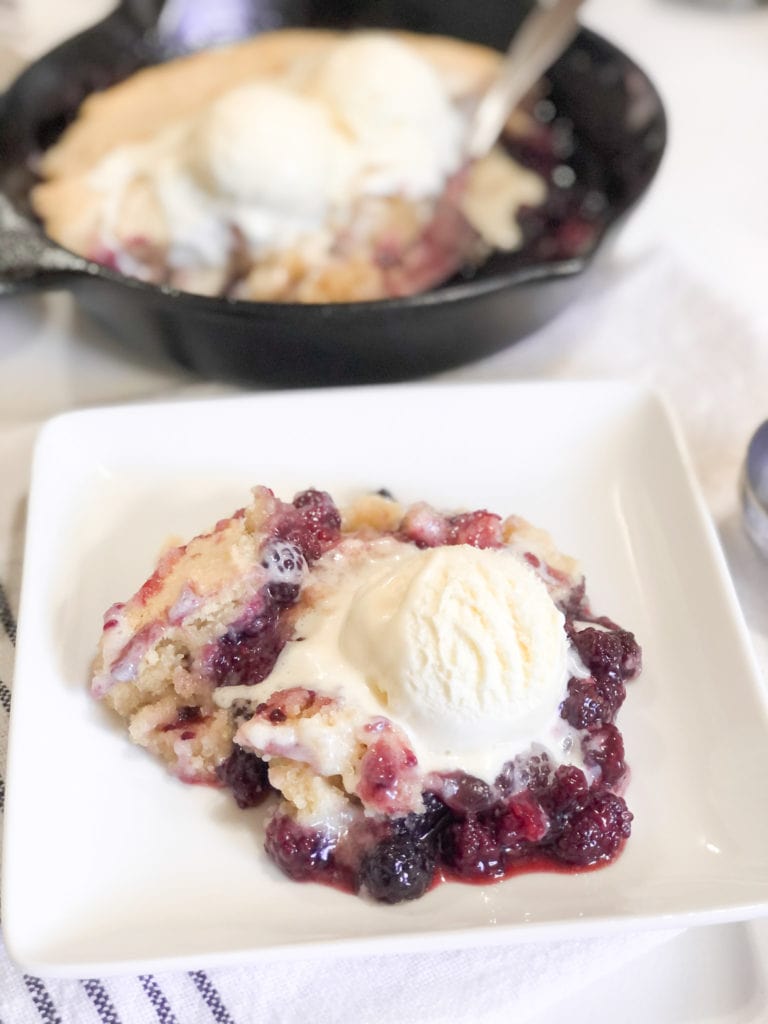 Close up of blackberry cobbler on white plate with ice-cream 