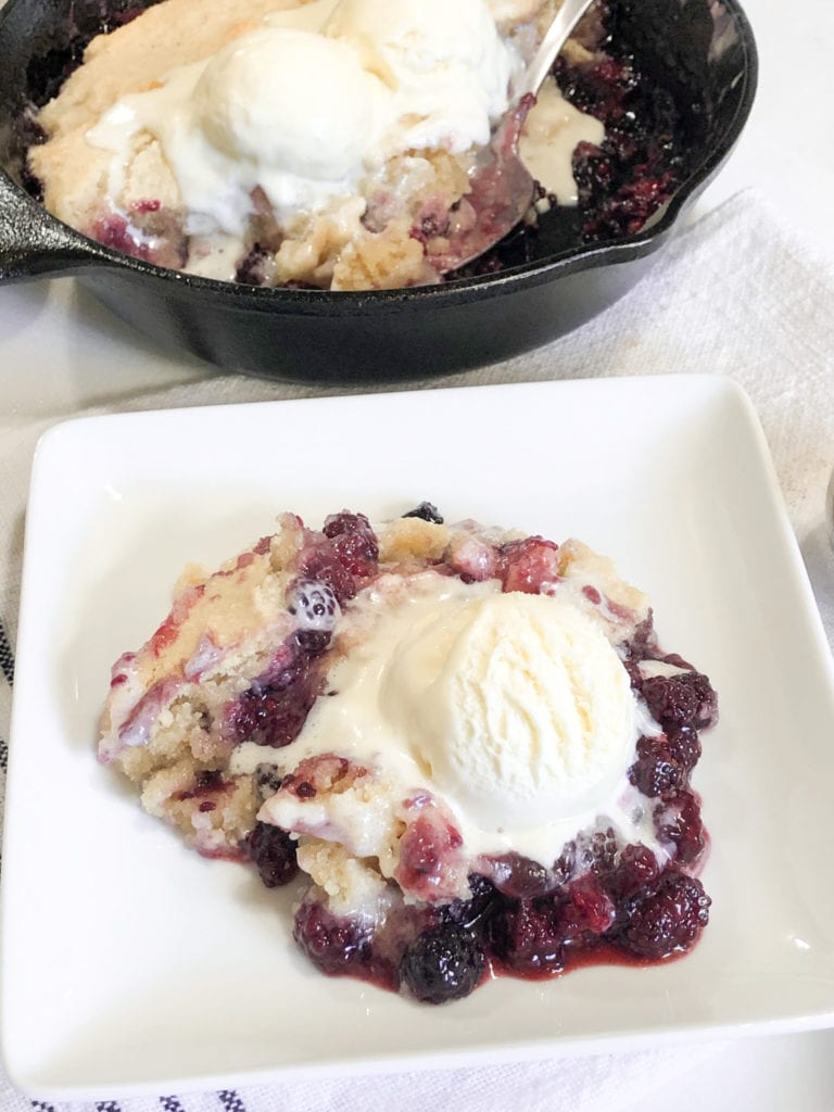 Close up of blackberry cobbler on white plate with ice-cream 