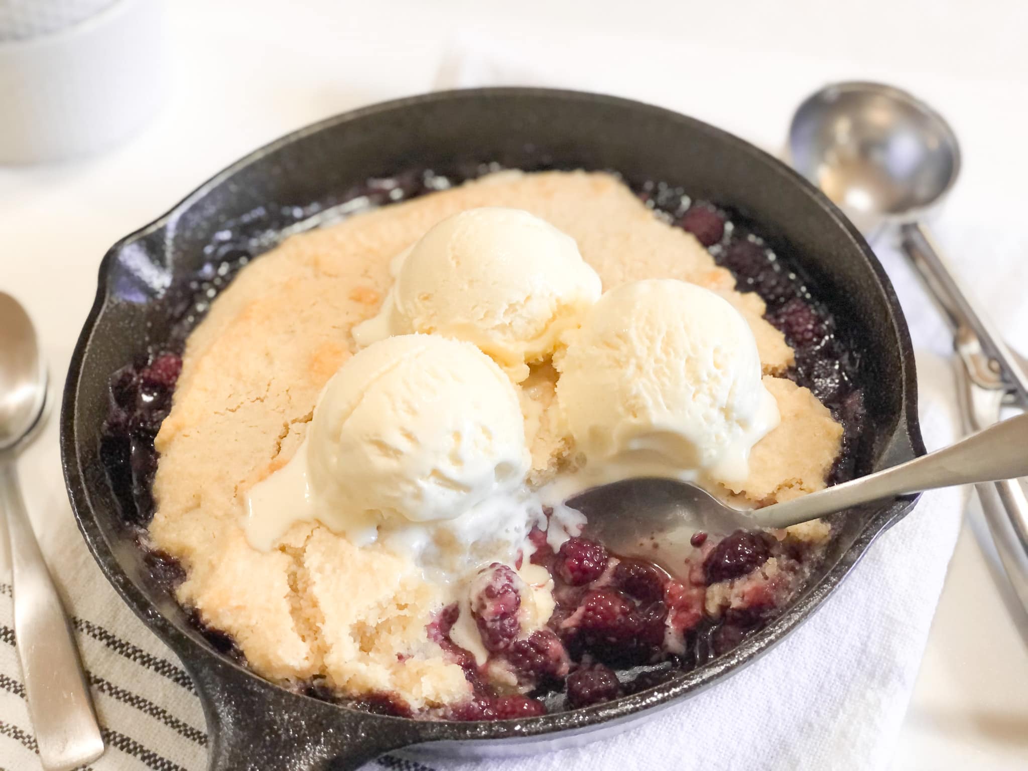 Close up of blackberry cobbler in iron skillet with ice-cream