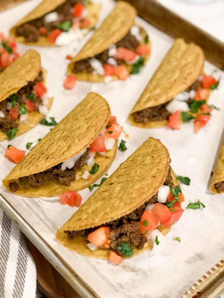 Close-up side few of crunchy tacos laying on sheet pan