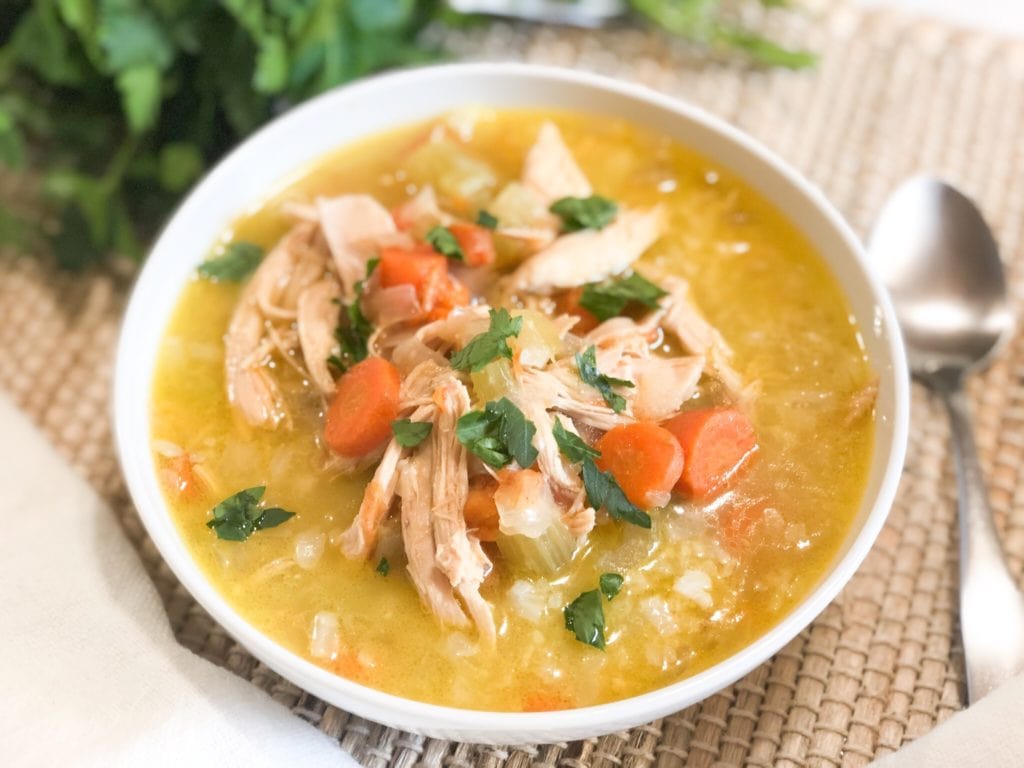 Close up of chicken-n-rice soup in white bowl.