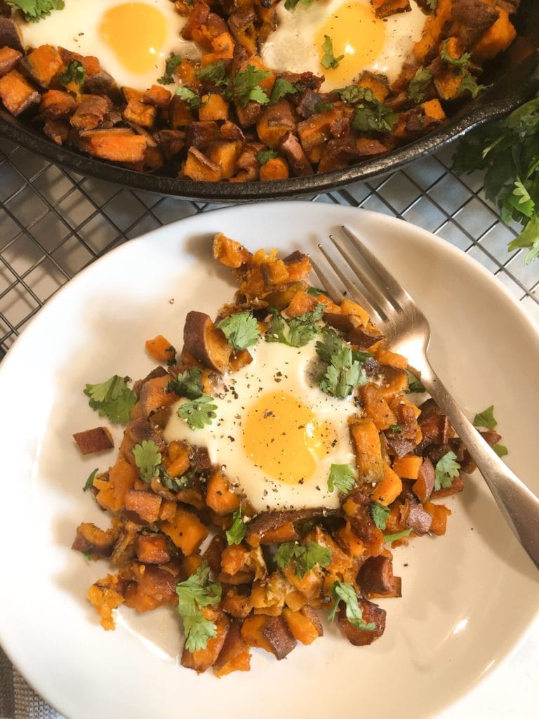 Close up of sweet potato hash and eggs on white plate