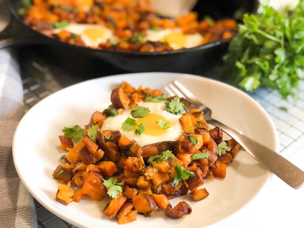 Close up of sweet potato hash and eggs on white plate
