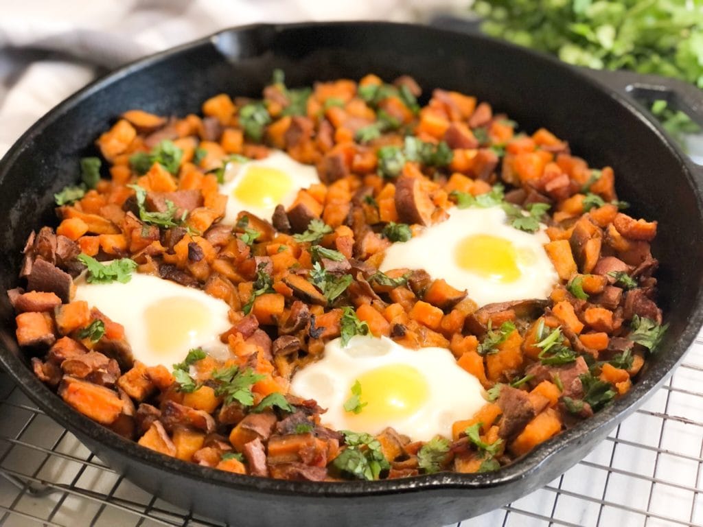 Close up of sweet potato hash and eggs in iron skillet