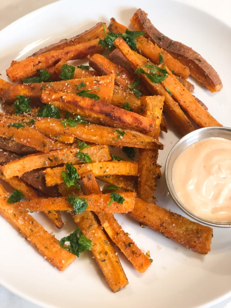 Close up of crispy sweet potato fries on white plate