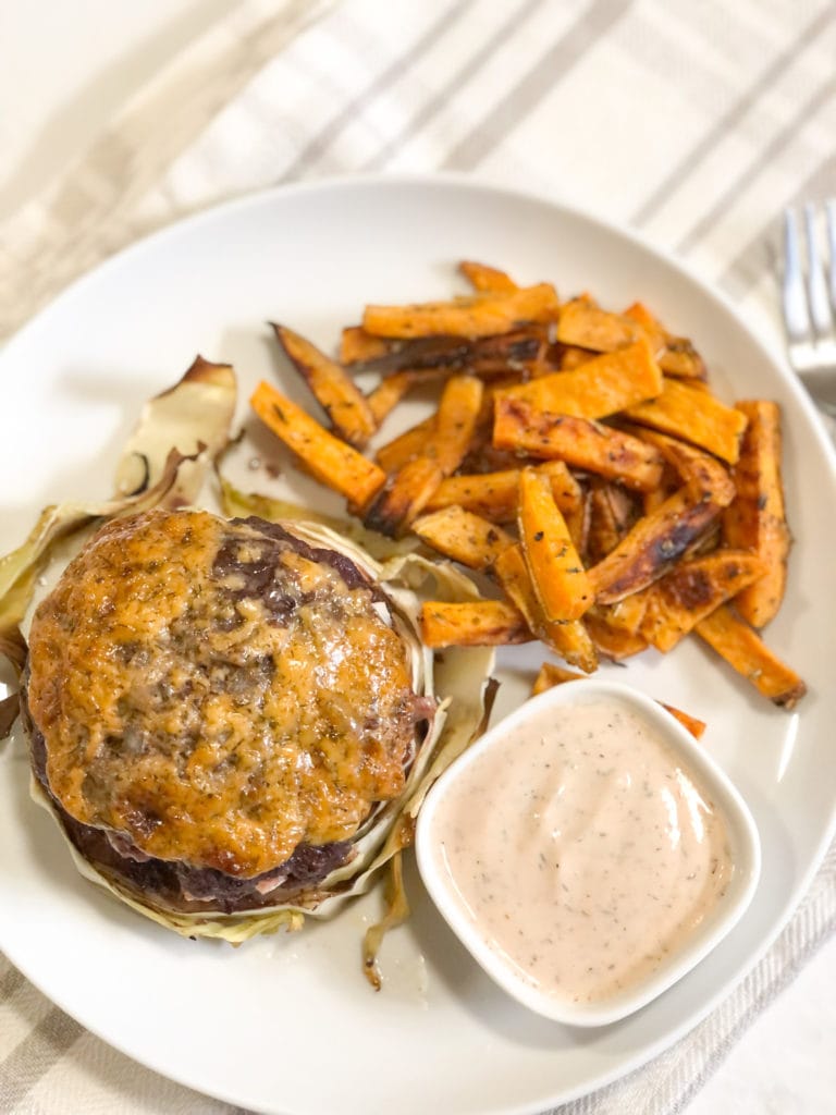 Close up of Paleo Beef Burgers -N- Cabbage on a white plate with crispy oven baked sweet potatoes fries and dipping sauce