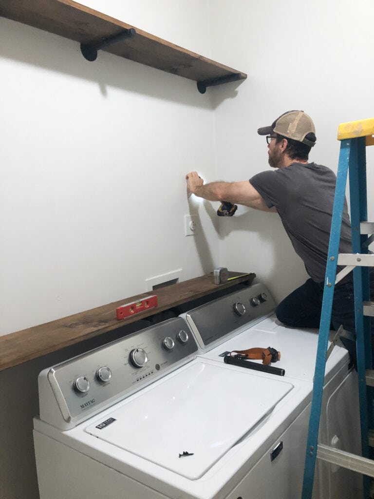 My husband putting the shelving on the walls
